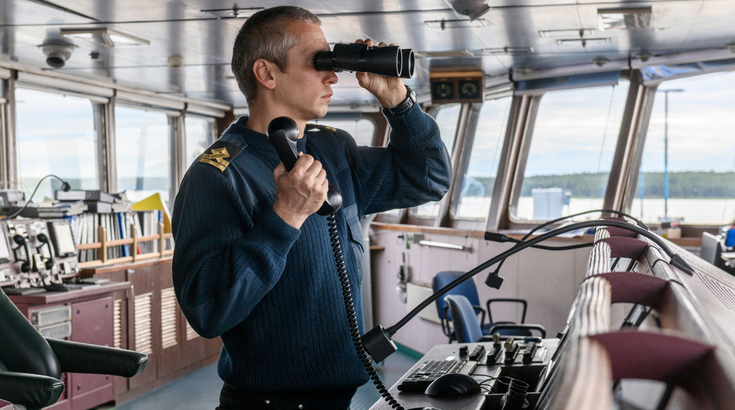 Capitaine professionnel à la barre d'un catamaran moderne avec des passagers visibles en arrière-plan