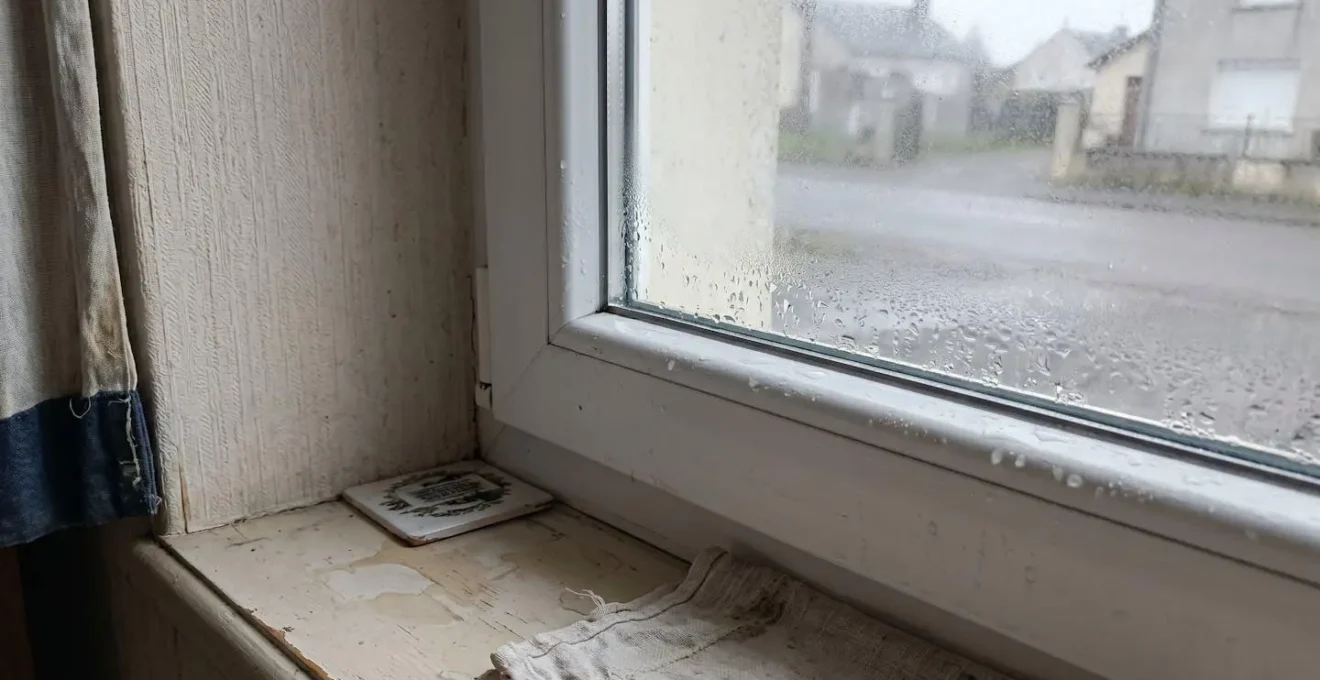 Traces de condensation et d'humidité visibles sur le bas du dormant d'une fenêtre PVC blanche récemment installée, vue rapprochée intérieur