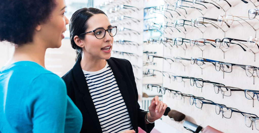 Opticien conseillant une cliente sur le choix de montures dans une boutique française moderne