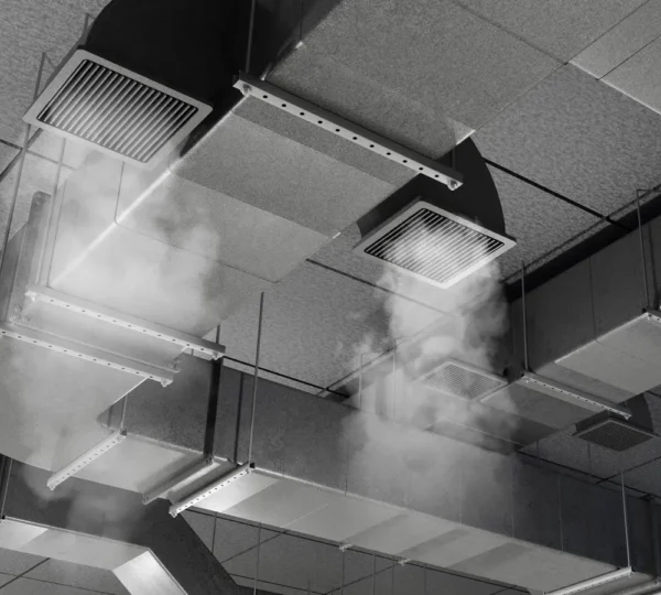 Technicien HVAC inspectant une unité de traitement d'air commercial avec appareil de mesure dans une salle mécanique
